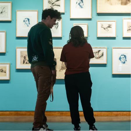 Two people viewing framed artworks in a gallery